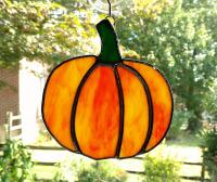 Stained glass pumpkin suncatcher made with orange and green opalescent art glass and measuring five inches in diameter. Comes with a suction cup hanger.