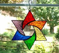Stained glass star of David made with rainbow colors of red, orange, yellow, green, purple, and blue textured cathedral art glass.  Measures six inches in diameter and comes with a suction cup hanger.