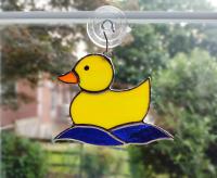 Yellow opalescent stained glass rubber duckie suncatcher with blue cathedral glass water waves underneath. Measures 5 1/4 inches by 4 inches, suction cup holder included. $35 plus $8.95 shipping