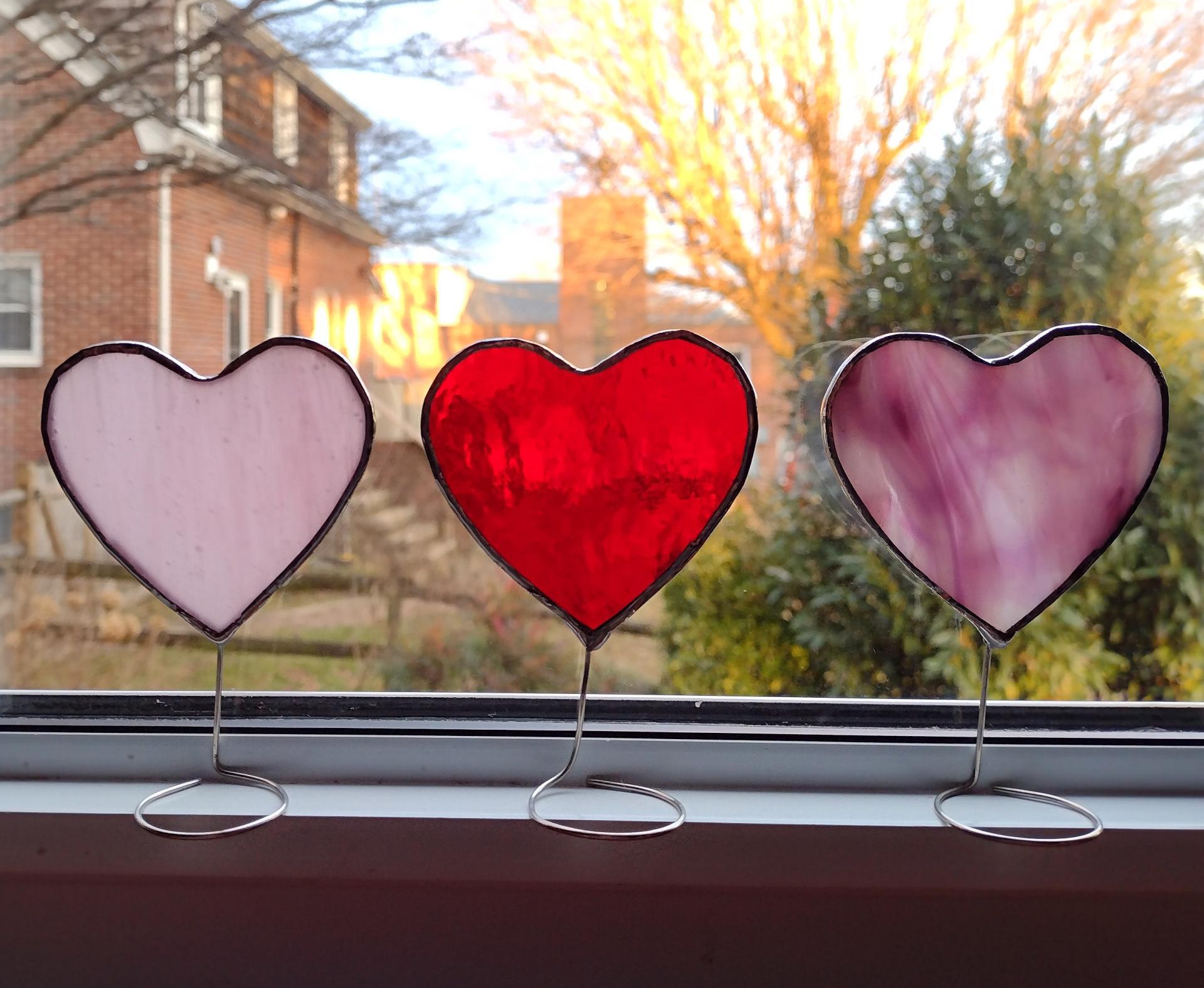 Set of three mini stained glass standing hearts available in three colors.  Pink, pink and white swirl, and red glass.  Stand on a windowsill or tabletop with wire attached to the bottoms.
