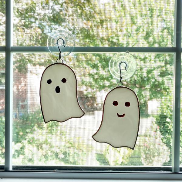 white opalescent stained glass ghost suncatchers with scary or happy faces painted on them. Measuring three inches by four inches and come with suction cup hangers. Your choice of face type. Priced at fifteen dollars each or thirty dollars for a set.