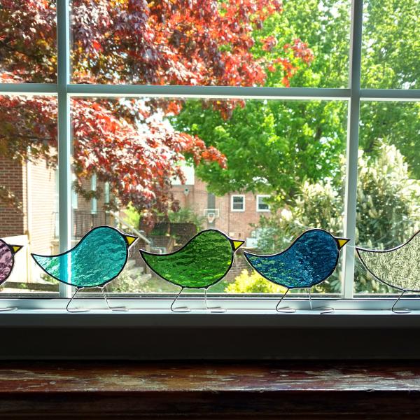 Stained glass standing birds that comes in three sizes of baby, child, parent, and in twelve birthstone colors of cathedral art glass.