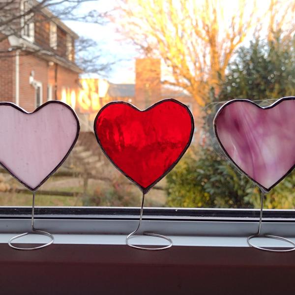 Set of three mini stained glass standing hearts available in three colors.  Pink, pink and white swirl, and red glass.  Stand on a windowsill or tabletop with wire attached to the bottoms.