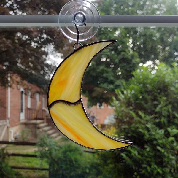 Stained glass crescent moon suncatcher, measures 4 1/2 in tall by 3 in wide.Made with orange and yellow swirled Corsica glass