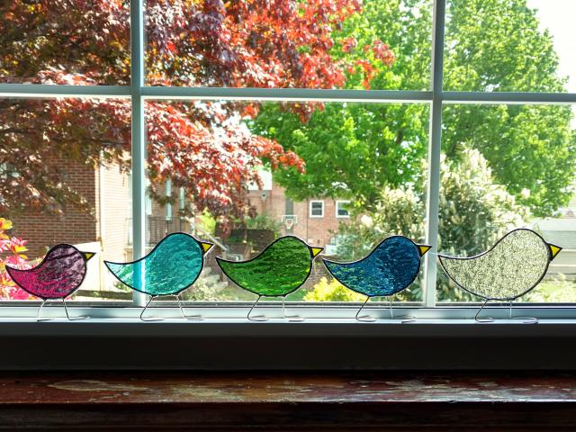 Stained glass standing birds that comes in three sizes of baby, child, parent, and in twelve birthstone colors of cathedral art glass.