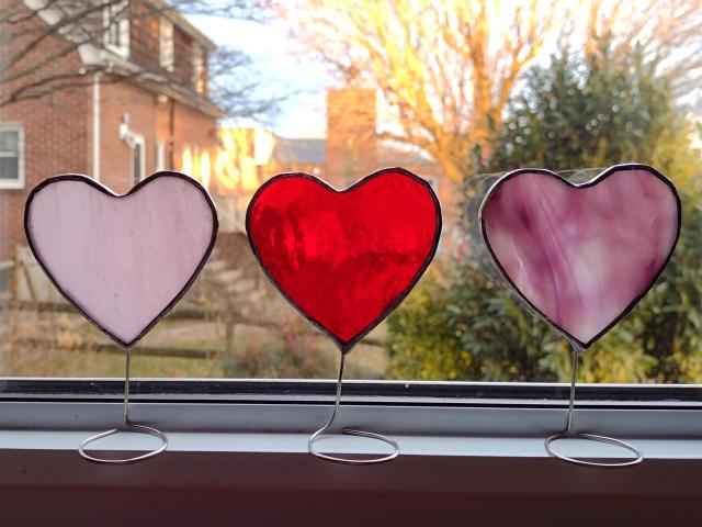 Set of three mini stained glass standing hearts available in three colors.  Pink, pink and white swirl, and red glass.  Stand on a windowsill or tabletop with wire attached to the bottoms.