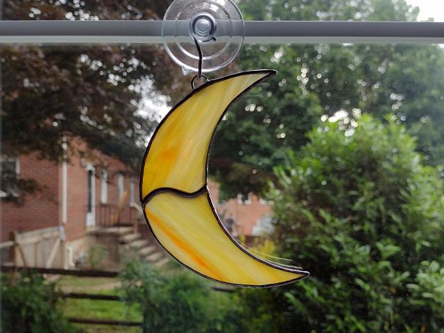 Stained glass crescent moon suncatcher, measures 4 1/2 in tall by 3 in wide.Made with orange and yellow swirled Corsica glass