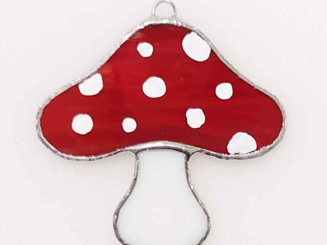 Red stained glass mushroom suncatcher with white spots and white stem.  Suction cup hanger included.