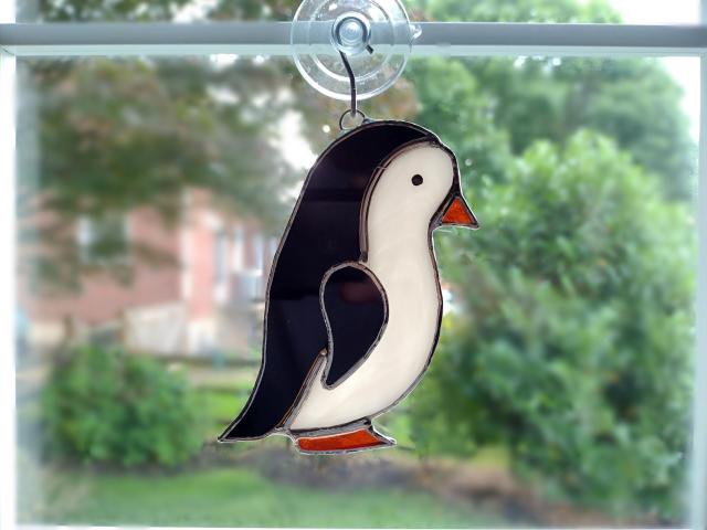 stained glass penguin available with a boy face or girl face, measures five inches by four inches and comes with a suction cup hanger.
